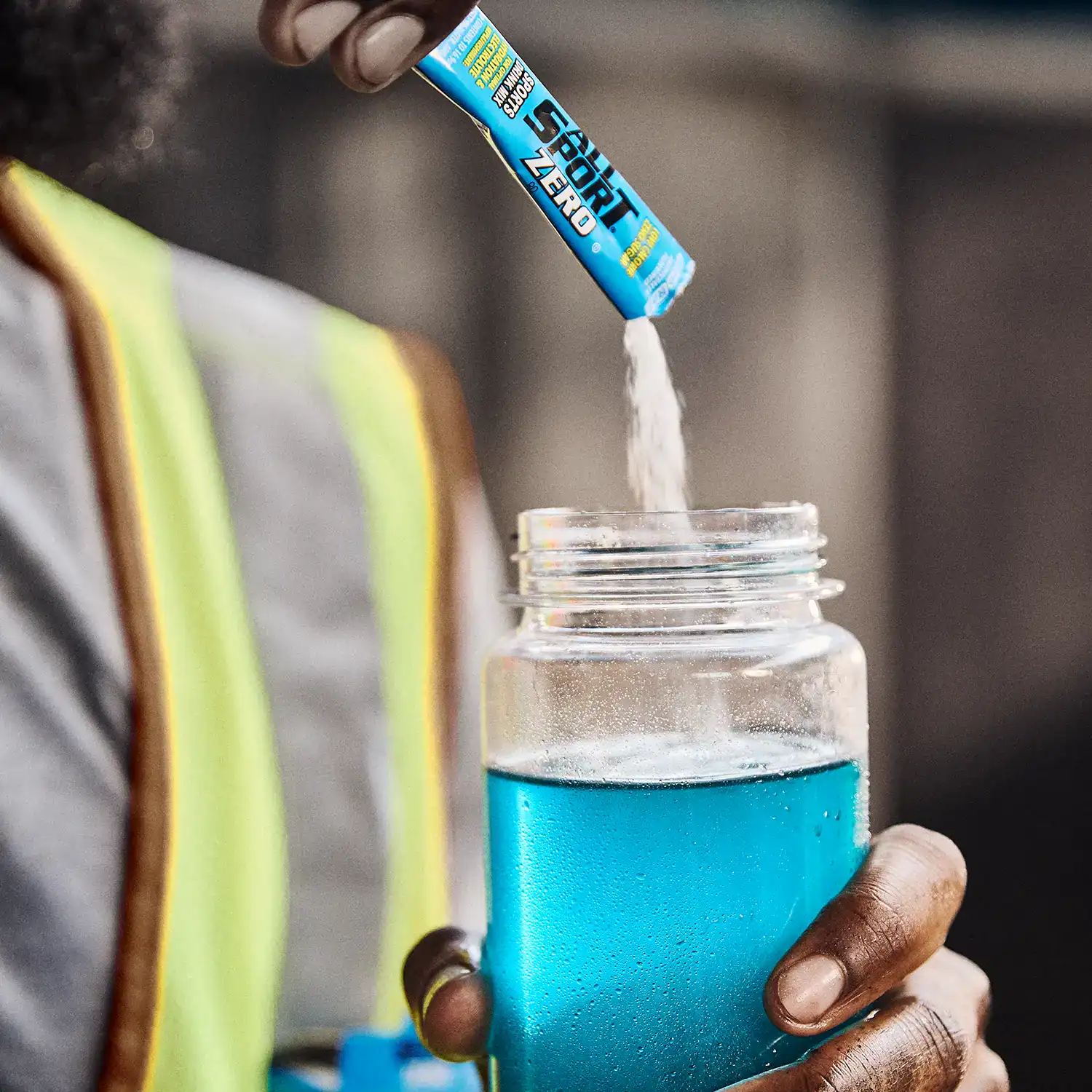 Worker pouring All Sport Zero Blue Raz into a clear water container