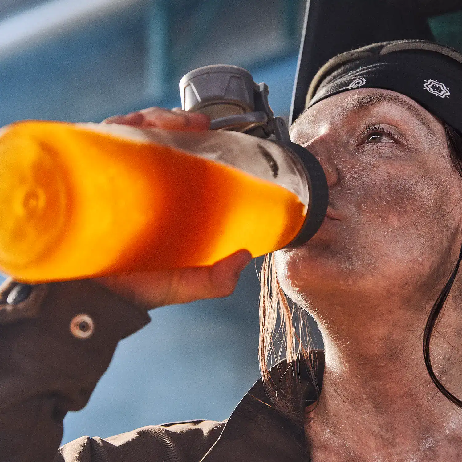 An industrial welder drinking All Sport from a clear container.